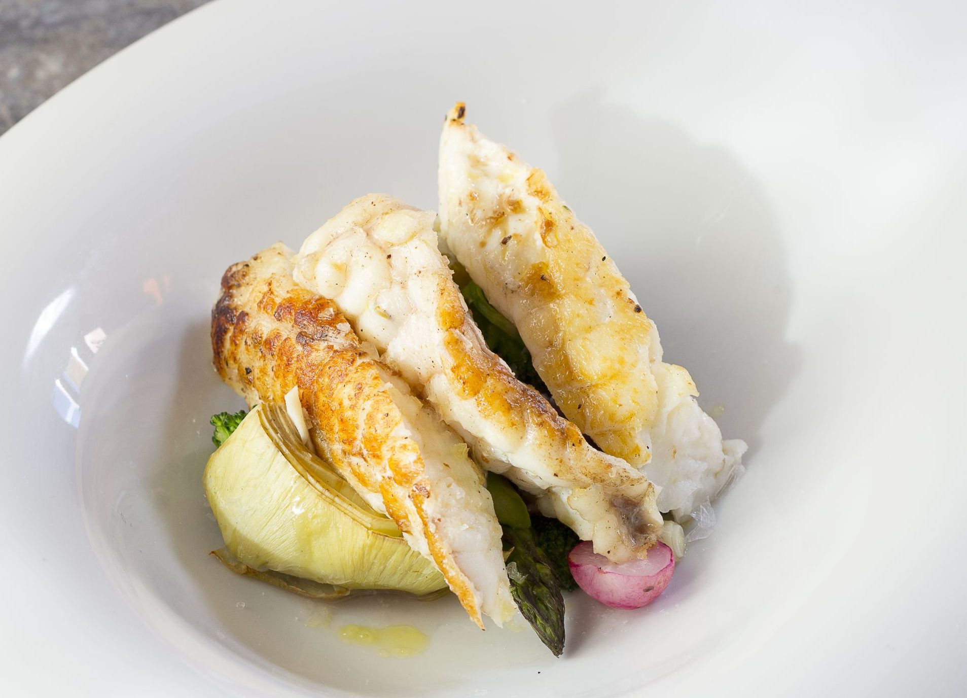 Plato de pescado blanco cocido acompañado por verduras a la parilla